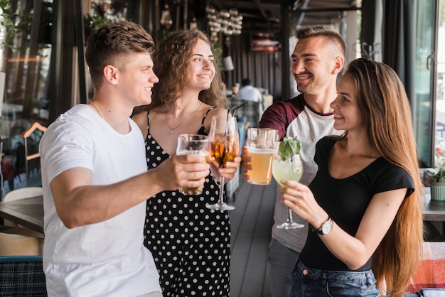 アルコールを持っている笑顔の友人のグループは、トーストを作るセットを飲みます