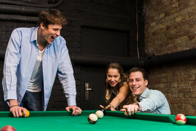 Group of smiling friends playing snooker enjoying in club