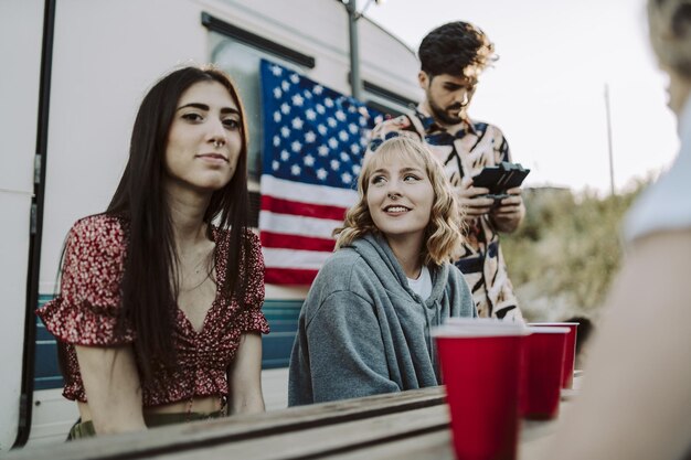 Group of Spanish friends having fun near the camp trailer with an American flag on it