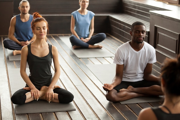 Group of sporty people in Sukhasana pose