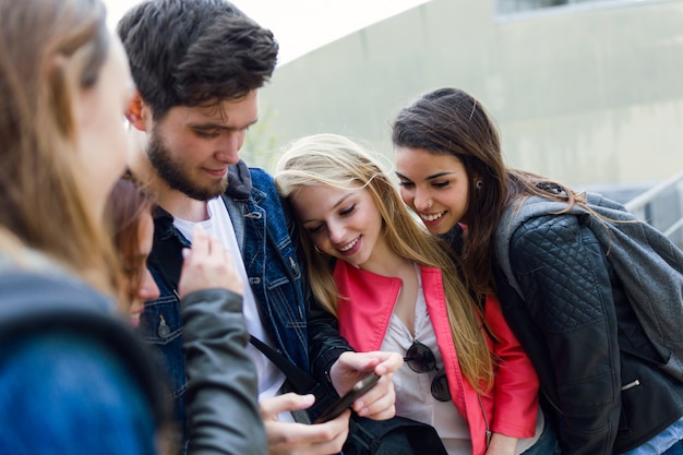 Group of students having fun with smartphones after class.