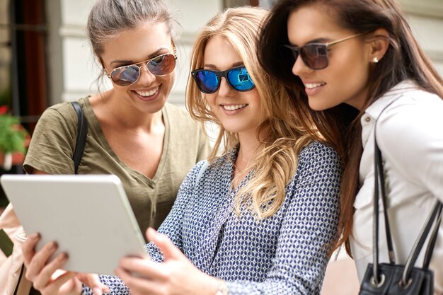 Группа стильных женщин, наслаждающихся в городе и использующих цифровой планшет