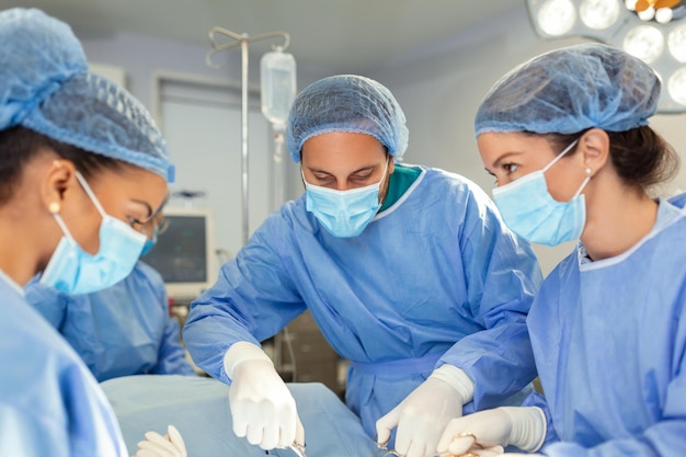 Группа хирургов, делающих операцию в операционной больницы Медицинская бригада, делающая критическую операцию Группа хирургов в операционной с хирургическим оборудованием Современное медицинское образование