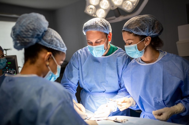 病院の手術室で手術を行う外科医のグループ重要な手術を行う医療チーム手術器具を備えた手術室の外科医のグループ現代の医学的背景