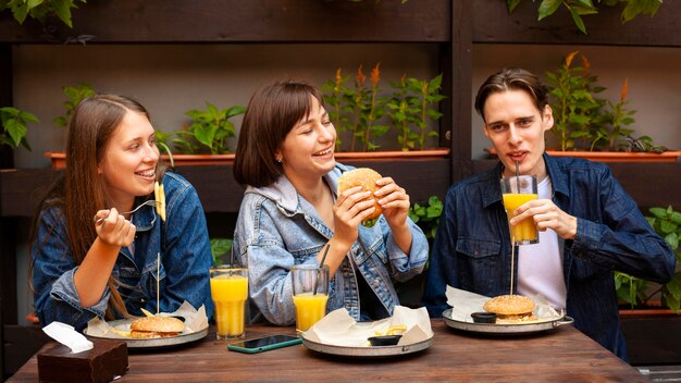 Group of three friends eating burgers