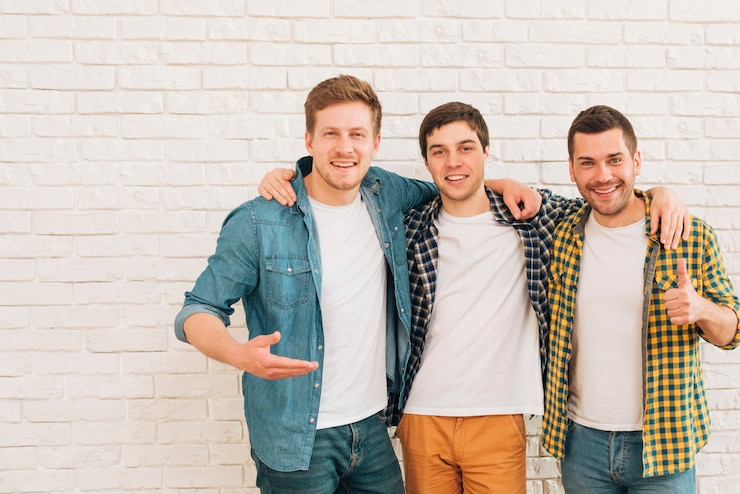 Free Photo group of three male friends standing together against white wall