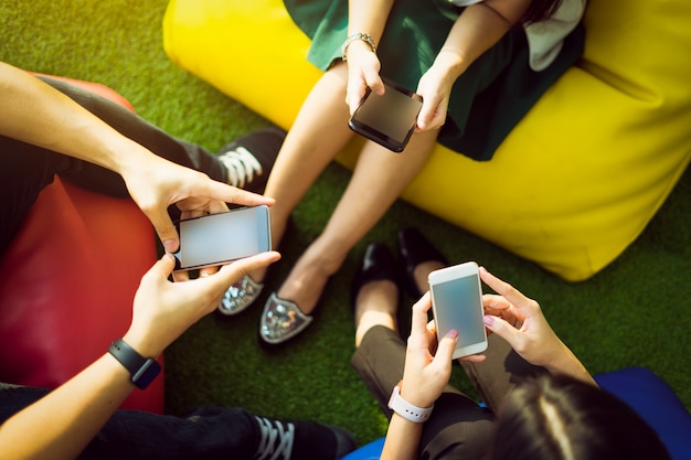 Группа из трех молодых людей, использующих смартфоны вместе, концепция современного образа жизни или коммуникационных технологий.