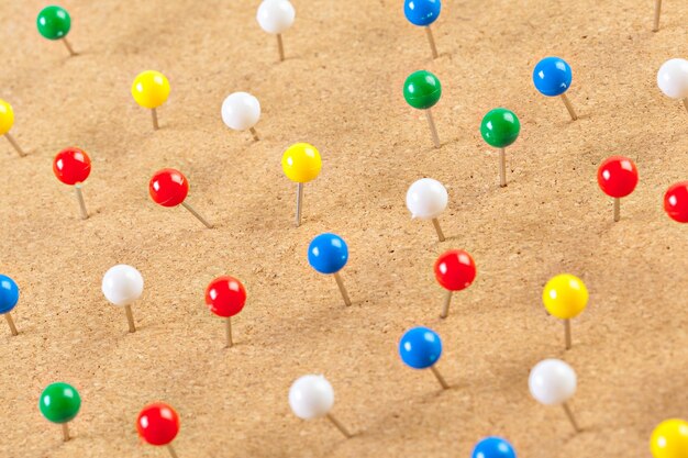 Group of thumbtacks pinned on corkboard