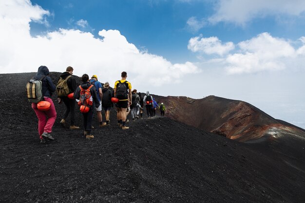 イタリア、シチリアのエトナ火山の上をハイキングする観光客のグループ