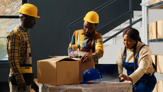 Group of trained workers using depot equipment, working in packaging department with packages. People using merchandise boxes to pack and ship products, industrial stock distribution.