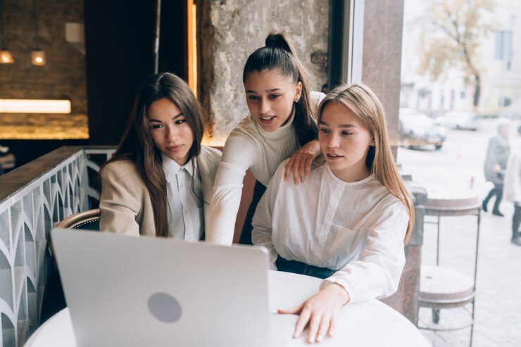 Free Photo a group of women friends in a cafe are looking at a laptop
