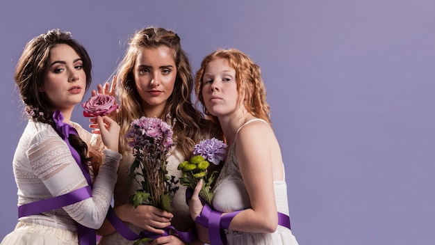 Free photo group of women posing with flowers and copy space