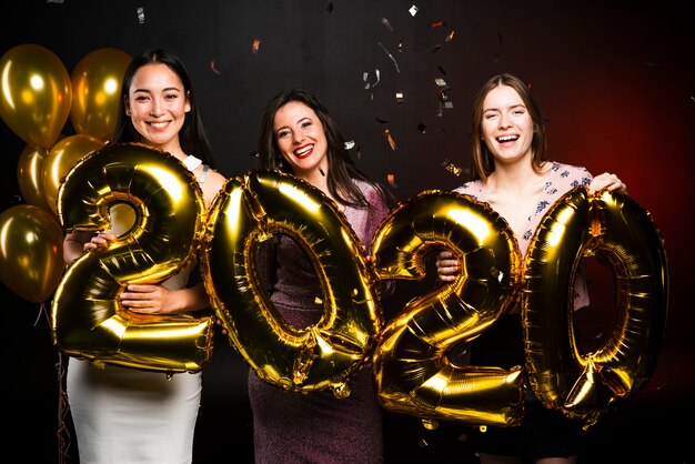 Group of women posing with golden balloons at new years party