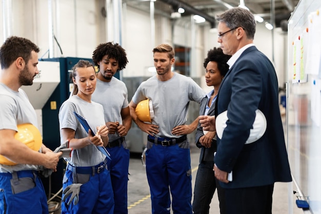 Foto gratuita gruppo di lavoratori che hanno un incontro con i dirigenti aziendali in una fabbrica il focus è sulla lavoratrice che presenta rapporti di sviluppo