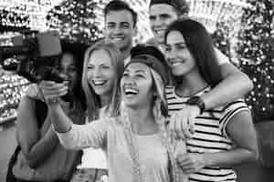 Free photo group of young adult friends taking a group selfie with a selfie stick