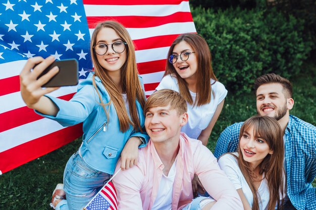 Группа молодых американцев делает селфи с американским флагом.