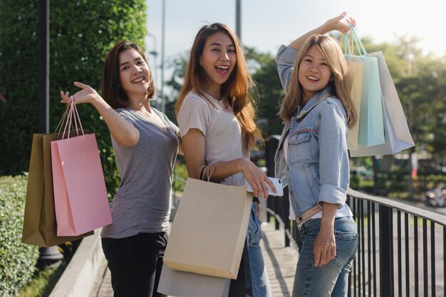 그들의 손에 쇼핑백과 야외 시장에서 쇼핑하는 젊은 아시아 여자의 그룹