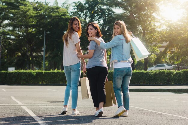 그들의 손에 쇼핑백과 야외 시장에서 쇼핑하는 젊은 아시아 여자의 그룹