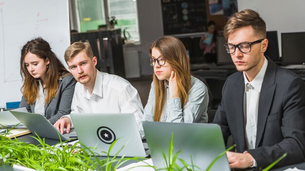 Group of young businesspeople using laptop at meeting