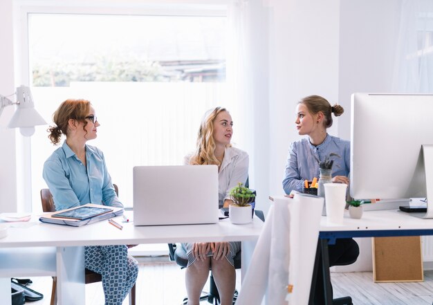 Group of young businesswomen sitting in modern office talking to each other