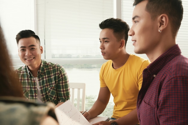 Gruppo di giovani uomini asiatici con indifferenza vestiti che si siedono e che parlano alla riunione