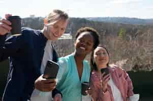 Free photo group of young friends celebrating the lifting of face mask restrictions by taking a selfie at the park