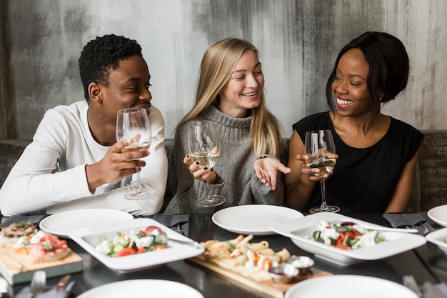 Foto gratuita gruppo di giovani amici che godono insieme della cena