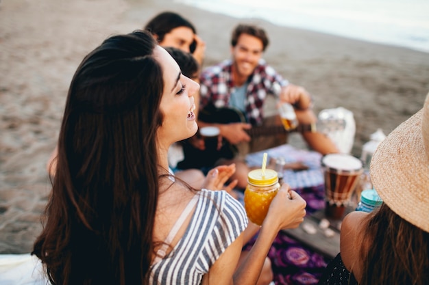 Foto gratuita gruppo di giovani amici seduti in spiaggia