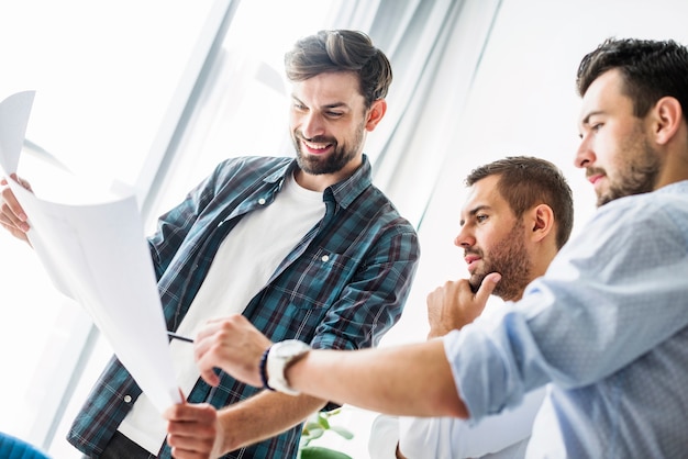 Group of young male architect analyzing blueprint