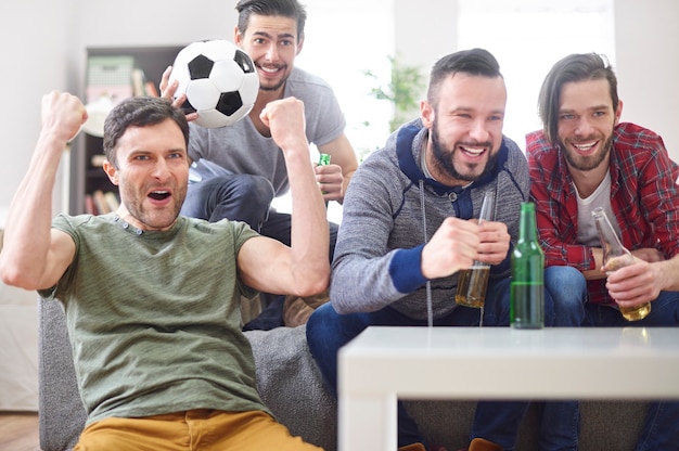 Группа молодых людей смотрят матч по телевизору