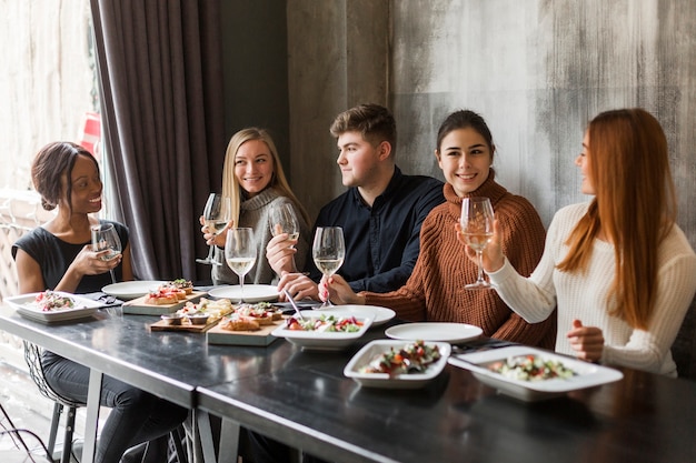 Foto gratuita gruppo di giovani che godono insieme della cena