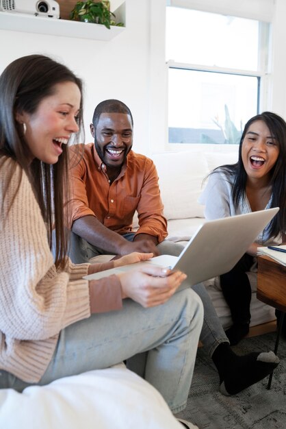 Group of young people using laptop together at home on sofa