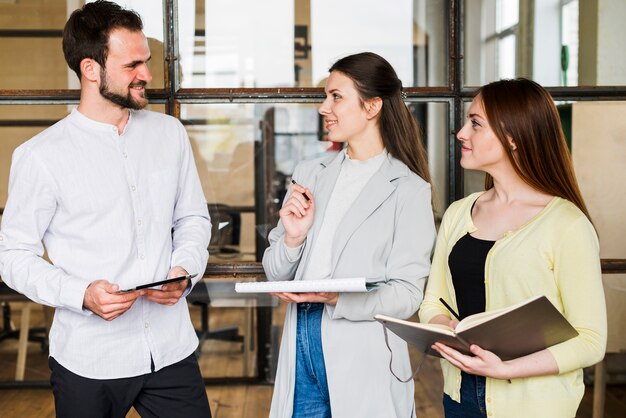 Group of young smiling businesspeople discussing project at office