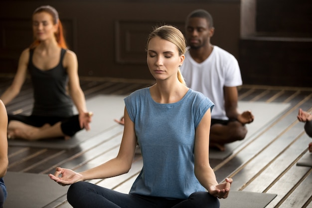 Group of young sporty people sitting in Easy Seat pose