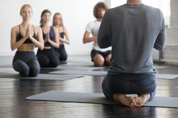 Group of young sporty people in vajrasana pose