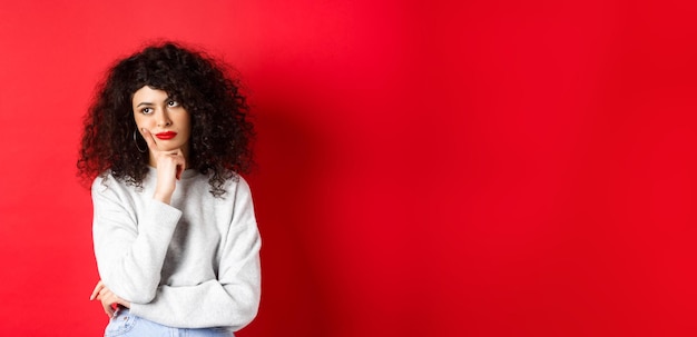 Grumpy young woman with curly hair looking annoyed or bored at empty space standing pensive and sad