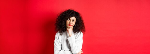 Grumpy young woman with curly hair looking annoyed or bored at empty space standing pensive and sad