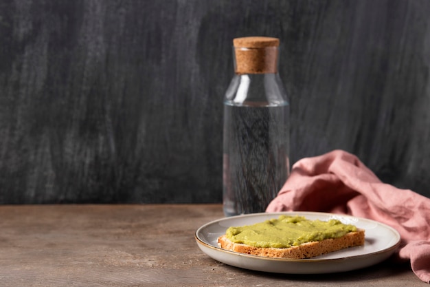 Foto gratuita guacamole su pane e bottiglia d'acqua