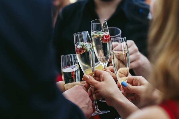 Guests clang glasses of champagne with delicious strawberries