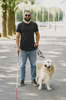Free photo guide dog helping blind man in the city. handsome blind guy have rest with golden retriever in the city.