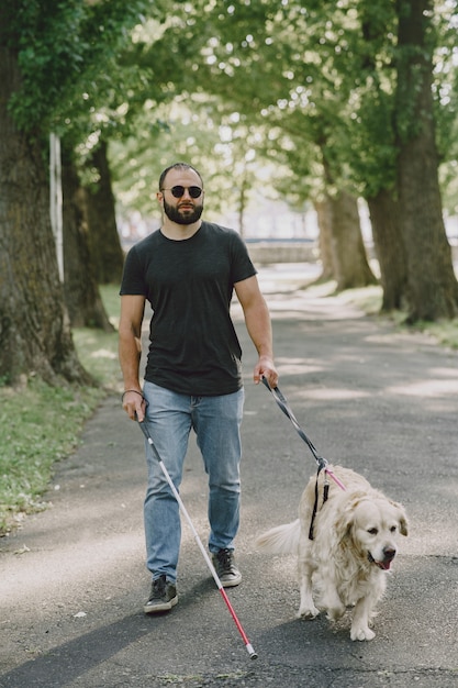 無料写真 盲導犬が市内の盲人を助ける。ハンサムな盲目の男は、街でゴールデン・リトリーバーと残りを持っています。