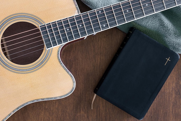 Free photo guitar and bible book on wooden background top view