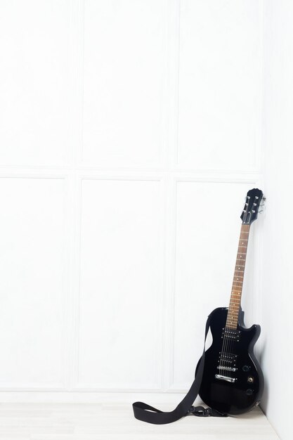 Guitar propped in front of a white wall