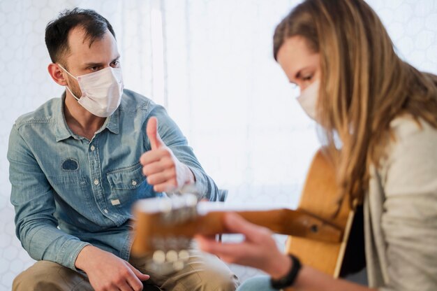 Guitar teacher giving thumbs up to female student