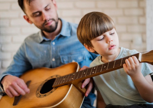 Guitar teacher showing child how to play at home