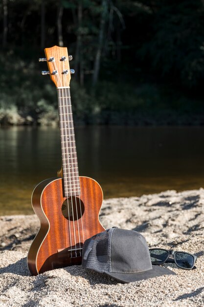 キャップと水面の近くの海岸にサングラスをかけたギター