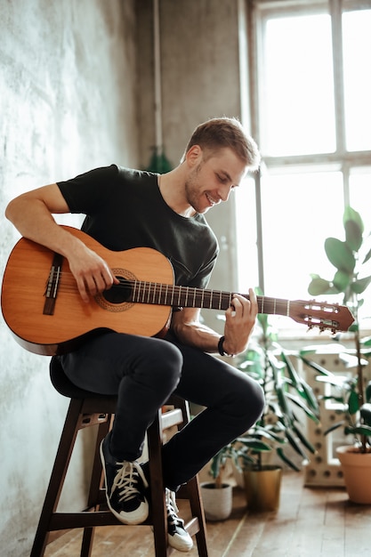 Uomo del chitarrista che gioca chitarra a casa