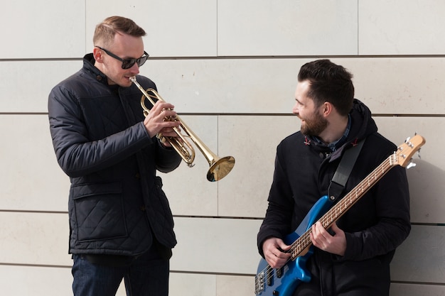 Guitarist watching trumpet player play his instrument