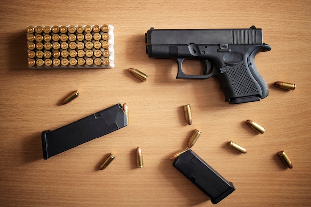 Gun with box of ammunition and bullets on wooden wall