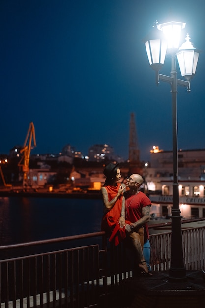 Бесплатное фото Парень и девушка обнимали друг друга на фоне ночного порта